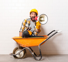 young bearded construction worker man on a wheelbarrow