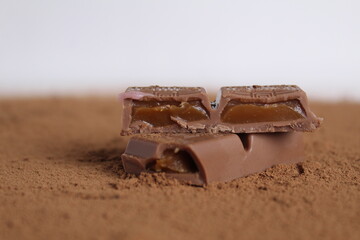 Chocolate stuffed with salted caramel lies on the cocoa on a white background there is room for text and copyspase the cover of the day of chocolate