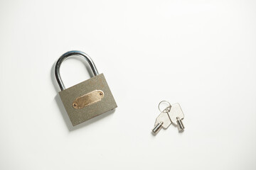 A gray metal padlock with a pair of keys on the white background. Top view