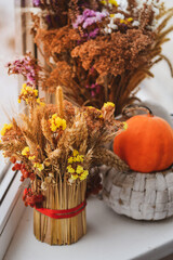  Autumn still life with pumpkin, wheat ears, dry poppy head, yellow and violet wildflowers. Selective focus