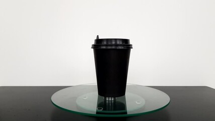 a disposable coffee cup rotates on a transparent platter