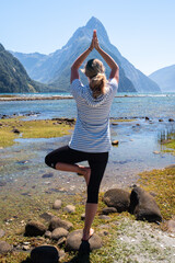 Athletic female practicing yoga outdoors, Milford Sound, New Zealand