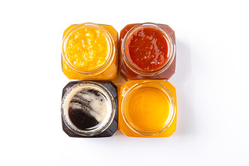 jars of peach and apricot jam and light and dark honey on a white background top view