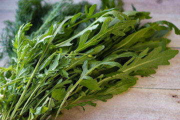 Green dill leaves and arugula on a wooden background