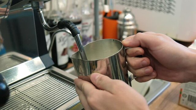 The barista makes coffee, grinds coffee in a coffee grinder, pours espresso, whips milk with a steamer, pours cappuccino and latte with a heart. The coffee machine is making an espresso. Failure