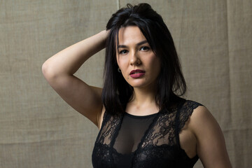 Portrait of a young sexy brunette girl in a lace top in dramatic tones. Vintage photo.