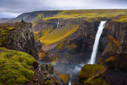Hiker standing at the edge of the Haifoss waterfall in Iceland