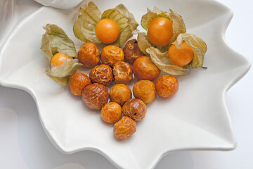Golden Berry, Physalis or Cape Gooseberry - Healthy Tropical Yellow-Orange Fruit. Fresh and Dried Fruits on a white Plate.