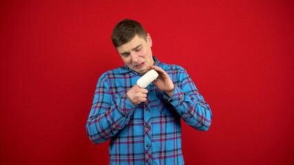 The young man's index finger is bandaged and sore. Shooting on a red background.