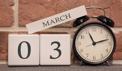 Important date, March 3, spring season. Calendar made of wood on a background of a brick wall. Retro alarm clock as a time management concept.