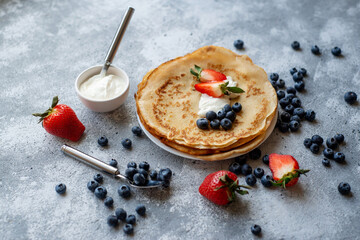 Pancakes with fresh strawberries and blueberries. National Russian cuisine, the holiday of Maslenitsa.