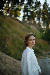 young girl in white linen clothes looks back on the blurred background of the forest. tenderness and youth