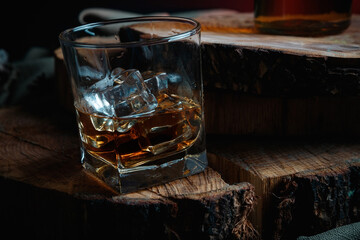 Ice cubes in a whiskey glass. Strong alcohol. Stand made of wood.