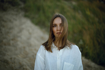 portrait of a young girl in white clothes on a blurred background of the forest. tenderness and loneliness