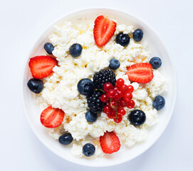 Cottage cheese with fresh strawberries and blueberries in a bowl for healthy breakfast, top view.