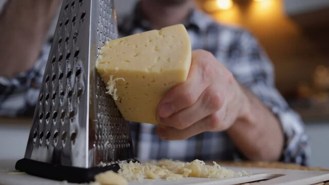 Man grating hard cheese at home. Slow motion close -up view