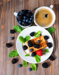 Waffles with blueberries and raspberries on plate.