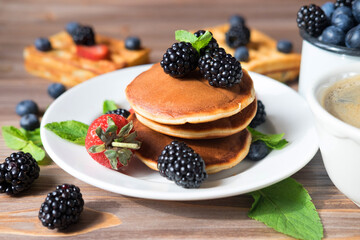 Pancakes for breakfast with blackberries and strawberries. Fluffy and delicious buttermilk pancakes.
