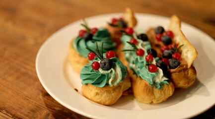 Tasty French eclairs with icing, cream, fresh berries and sugar decor elements.