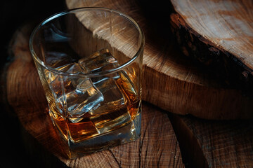 Ice cubes in a whiskey glass. Strong alcohol. Stand made of wood.
