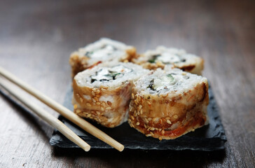 Sushi rolls with chopsticks on dark background