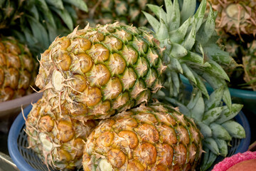 Bunch of whole, ripe pineapples photographed close up in thai street market