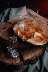 Glass of whiskey with ice on wooden surface