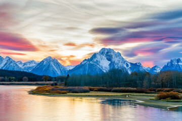 Picturesque view of the grand tetons glowing blue in this autumn sunset. beautiful reflections a smooth in the waters foreground from long exposure