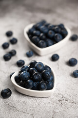 Fresh blueberries in a small heart shaped plate on a concrete background. Top view. Rustic. Creative valentine card