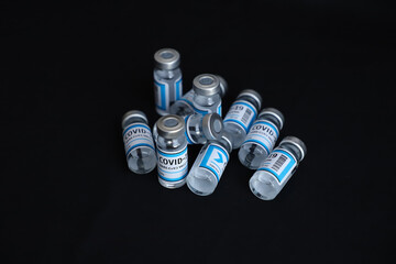 COVID 19 vaccine injection bottles on black background - overhead shot