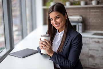 Portrait of smiling businesswoman sitting and holding a coffee cup.