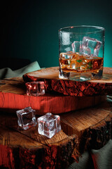 Glass of whiskey with ice on wooden surface