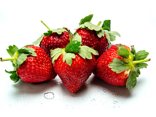 Five fresh ripe strawberry on a white surface with water beads
