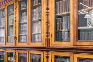 Many old books on the shelves of the university library. Retro books are behind the glass of a bookcase.