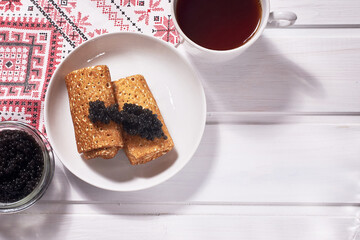 Pancakes with black caviar on a white wooden background. A traditional treat for Shrove Tuesday.