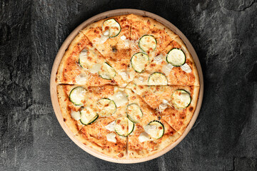 Hot tasty traditional italian pizza with salami, meat, cheese, tomatoes greens on a dark background
