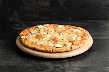 Hot tasty traditional italian pizza with salami, meat, cheese, tomatoes greens on a dark background