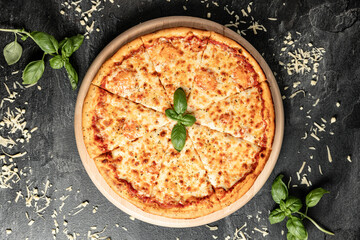 Hot tasty traditional italian pizza with salami, meat, cheese, tomatoes greens on a dark background