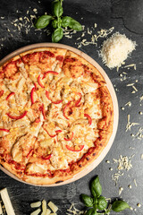 Hot tasty traditional italian pizza with salami, meat, cheese, tomatoes greens on a dark background
