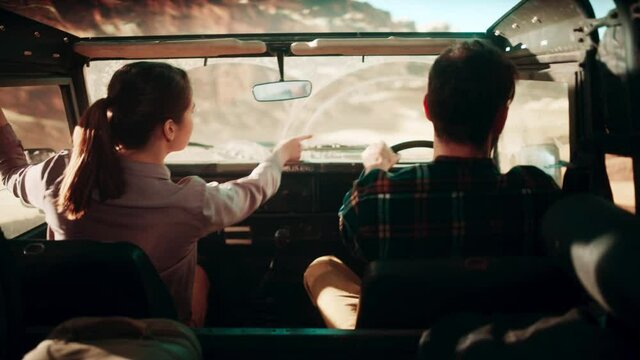 Happy Couple of Tourists Driving Off Road SUV, Riding Through the Desert Rocky Canyon