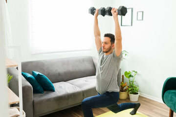 Fototapeta na wymiar Hispanic man working out with weights at home
