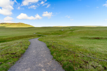 Fototapeta na wymiar Deserted winding gravel path running through a meadow in Iceland on a clear summer day. Concept of solitude.