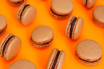Homemade Chocolate cocoa macaron cookies filled with chocolate hazelnut ganache on an orange background