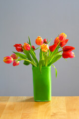 A vase of yellow and orange tulip flowers in a green vase
