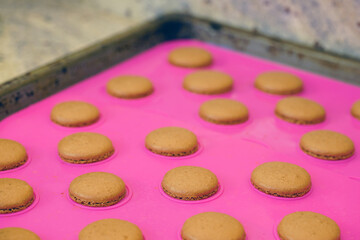 Obraz na płótnie Canvas Homemade chocolate raspberry macaron cookies on a pink silicone mat on a baking sheet