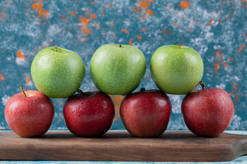 Red and green apples isolated on a wooden board