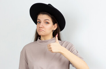 Happy young female making thumb up sign and smiling cheerfully, showing her support and respect to...