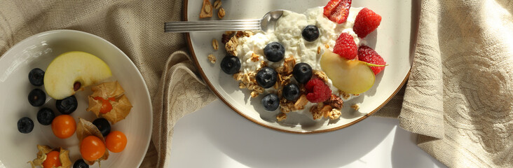 Healthy breakfast yogurt bowl with granola and berries. Rustic backgroundwith morning sun light. Concept of clean eating, dieting and weight loss. Horizontal top view, flat lay