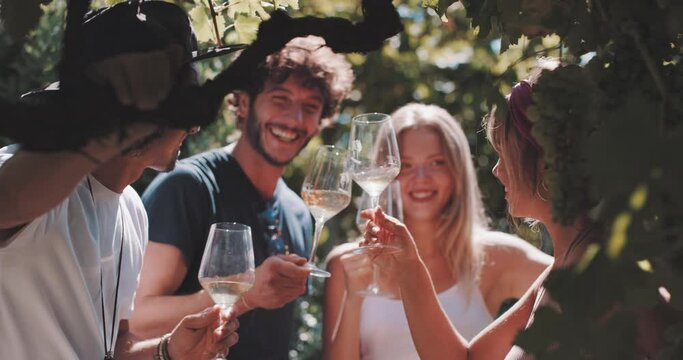 Group of happy friends raising hands toasting with wine in the vineyard