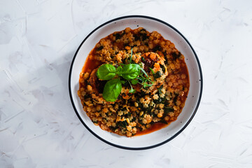 vegan meatballs with tomato sauce and tiny pasta topped with basil and herbs, healthy plant-based food